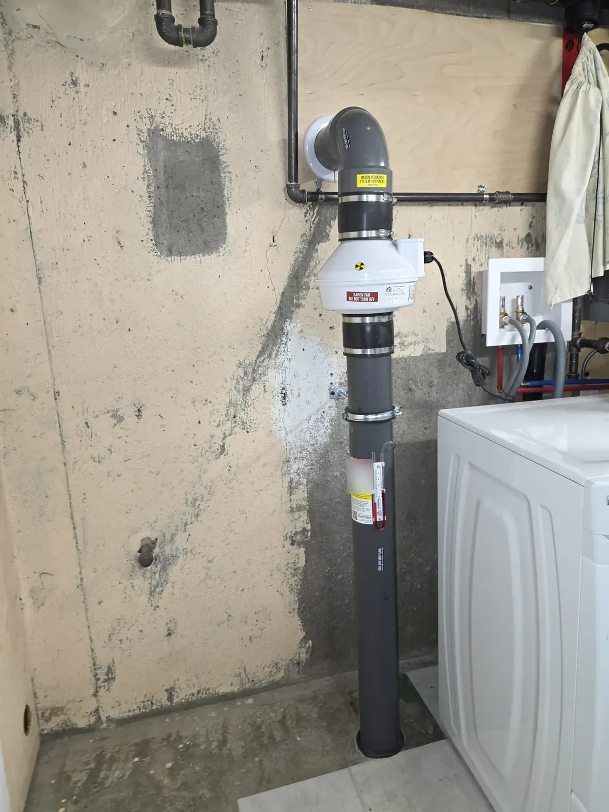 Radon system with the pipe exiting through the rim joist in an older basement with a concrete foundation wall
